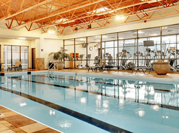 A large indoor swimming pool with a tiled floor and a high ceiling with exposed beams.